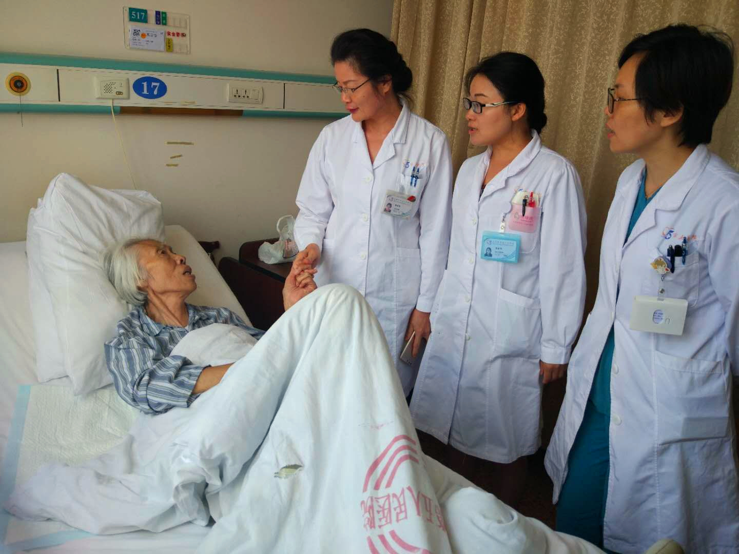 术后查房，曾被子宫内膜病变折磨的奶奶紧紧抓住陈亚萍的手表示感谢.jpg