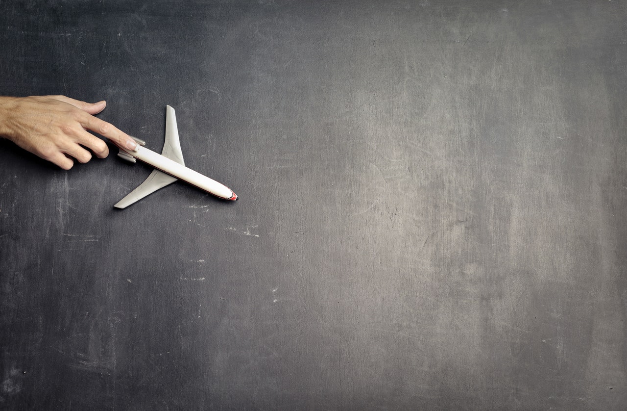 anonymous-person-with-miniature-airplane-on-chalkboard-3769120.jpg