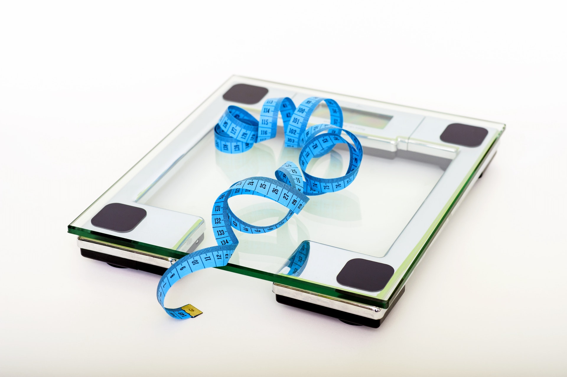 blue-tape-measuring-on-clear-glass-square-weighing-scale-53404.jpg